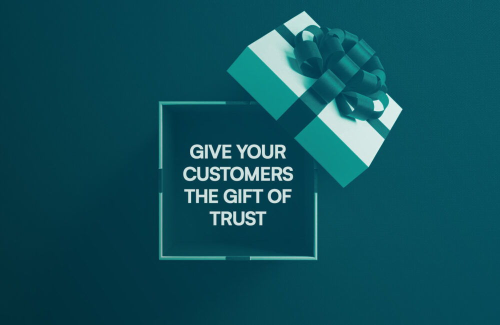A teal and white Christmas gift box against a teal background. Inside the box is a message: “Give your customers the gift of trust.”