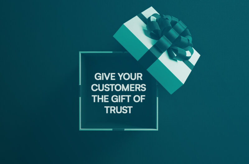 A teal and white Christmas gift box against a teal background. Inside the box is a message: “Give your customers the gift of trust.”
