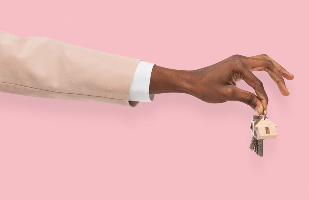 A hand holding house keys against a pink background, symbolizing secure and verified rental transactions.