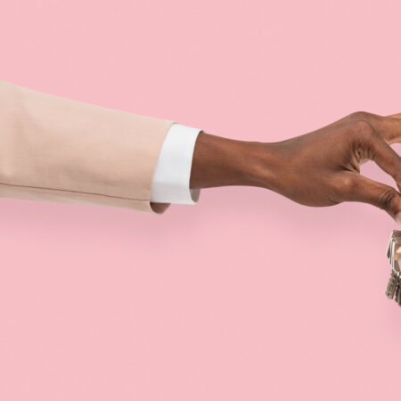 A hand holding house keys against a pink background, symbolizing secure and verified rental transactions.