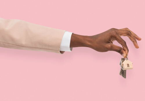 A hand holding house keys against a pink background, symbolizing secure and verified rental transactions.