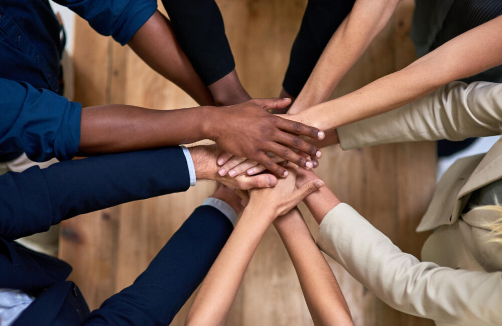 Several hands stacked together to symbolize trust, unity, and strong workplace relationships.