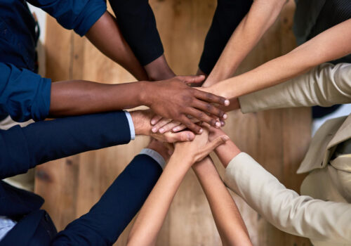 Several hands stacked together to symbolize trust, unity, and strong workplace relationships.