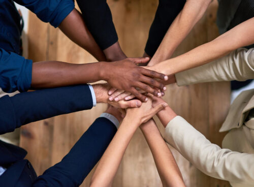 Several hands stacked together to symbolize trust, unity, and strong workplace relationships.
