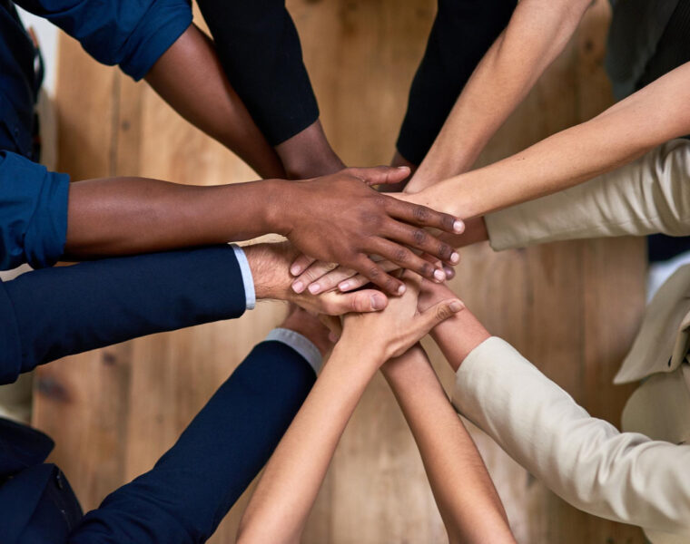 Several hands stacked together to symbolize trust, unity, and strong workplace relationships.