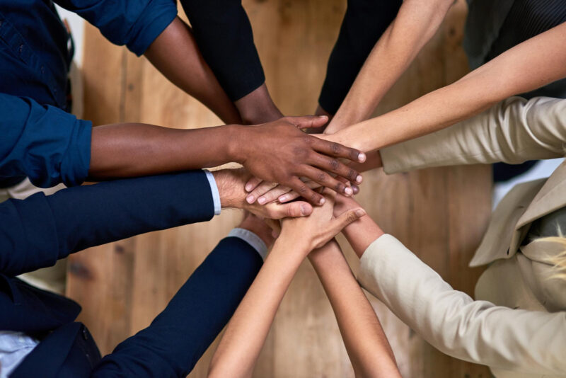 Several hands stacked together to symbolize trust, unity, and strong workplace relationships.