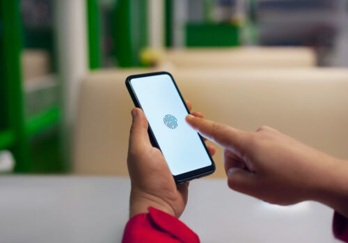 Hand holding smartphone displaying biometric fingerprint scan for secure mobile identity verification.