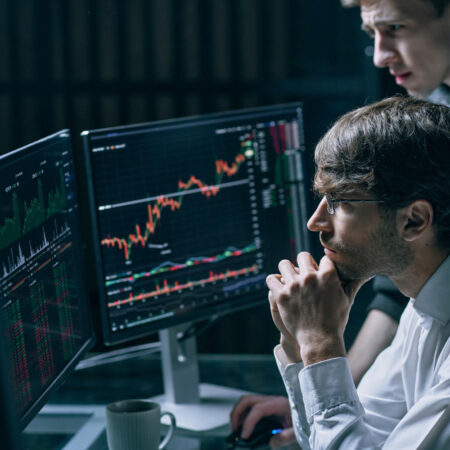 Two professionals reviewing financial data and transaction graphs on a laptop for Anti-Money Laundering (AML) compliance analysis.