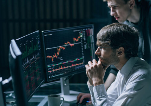 Two professionals reviewing financial data and transaction graphs on a laptop for Anti-Money Laundering (AML) compliance analysis.