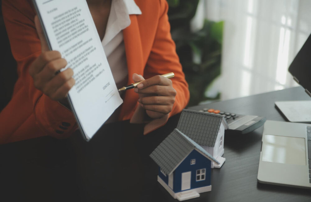 Person holding paperwork and pointing with a pen to the signature during mortgage loan process.