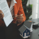 Person holding paperwork and pointing with a pen to the signature during mortgage loan process.