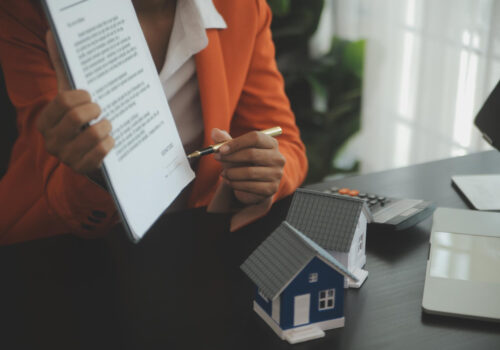 Person holding paperwork and pointing with a pen to the signature during mortgage loan process.