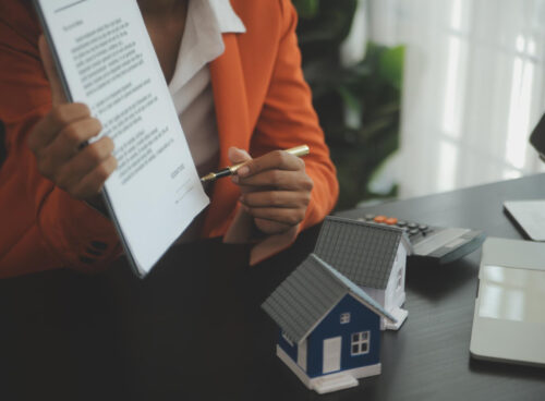 Person holding paperwork and pointing with a pen to the signature during mortgage loan process.