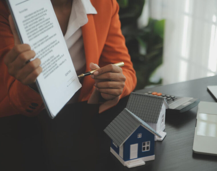 Person holding paperwork and pointing with a pen to the signature during mortgage loan process.