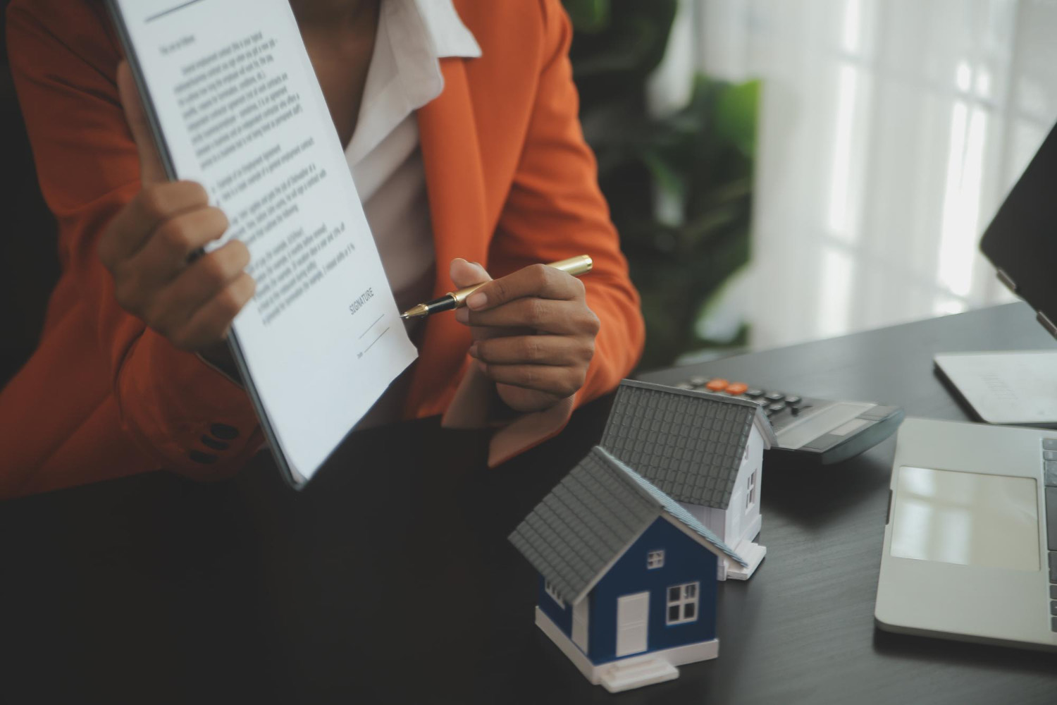 Person holding paperwork and pointing with a pen to the signature during mortgage loan process.